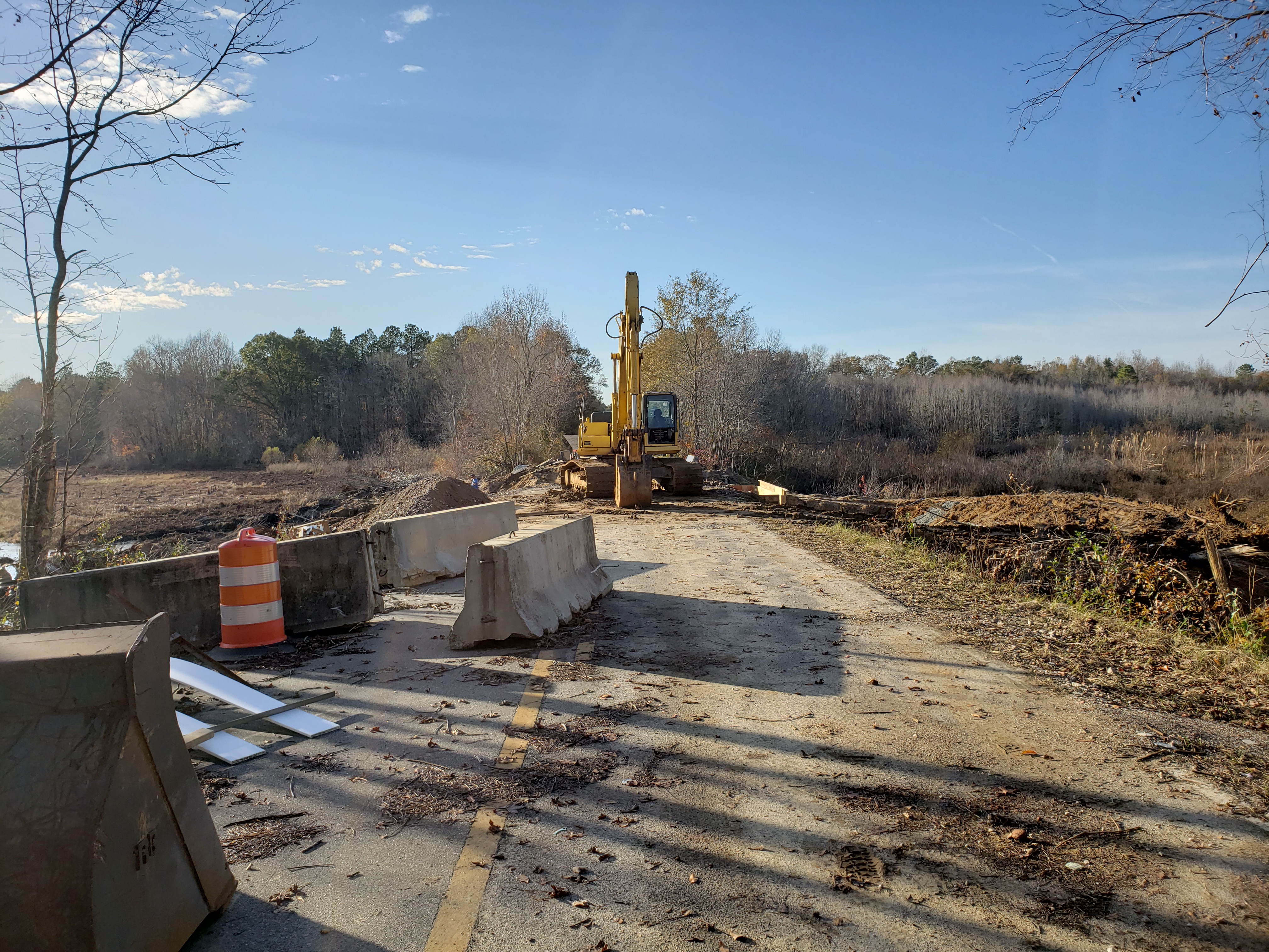 Excavator clearing and repairing a site roadway
