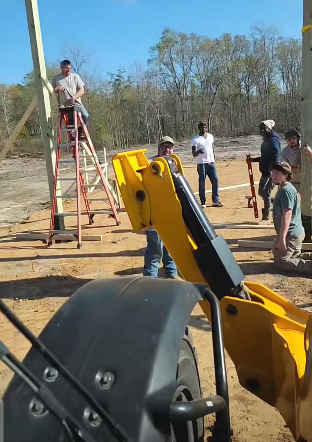 Crew setting posts on site with heavy equipment